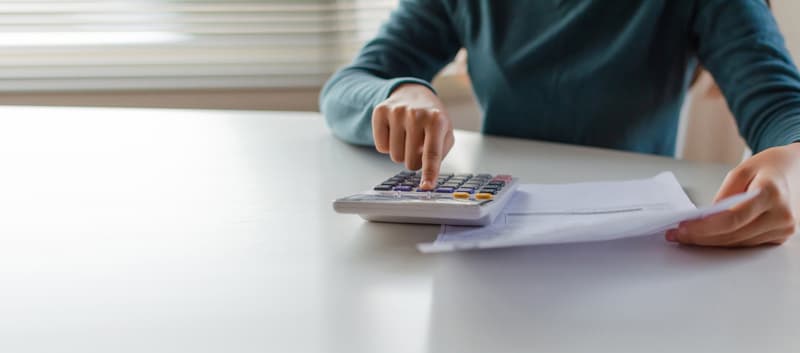 panoramic banner. hand of young woman using calculator for calculating family budget cost bills on desk in home office, plan money cost saving, investment, business finance, expenses, income .
