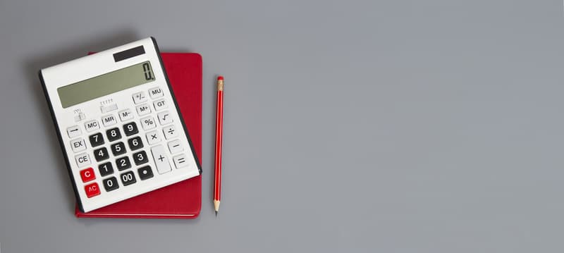 white calculator and red organizer on the grey table with red pencil