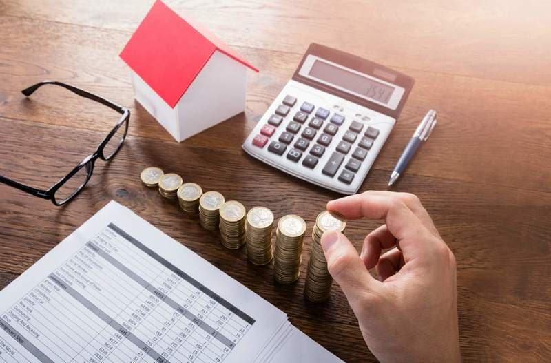 Person Stacking Coins On Wooden Desk