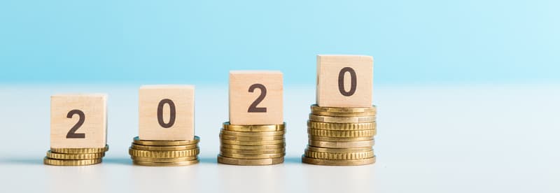2020 New year saving money and financial planning concept. Stack of coins w/ number 2020 on wood table over green background. Creative idea for business growth, investment, profit and banking.