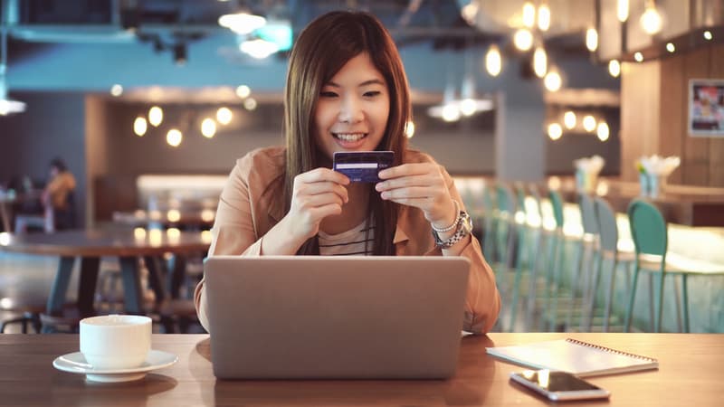Asian businesswoman in casual suit using the credit card with computer for online shopping at co-working space, business technology and lifestyle concept